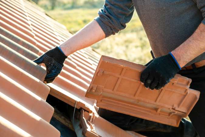 a man doing roofing upgrades by replacing the existing ones.